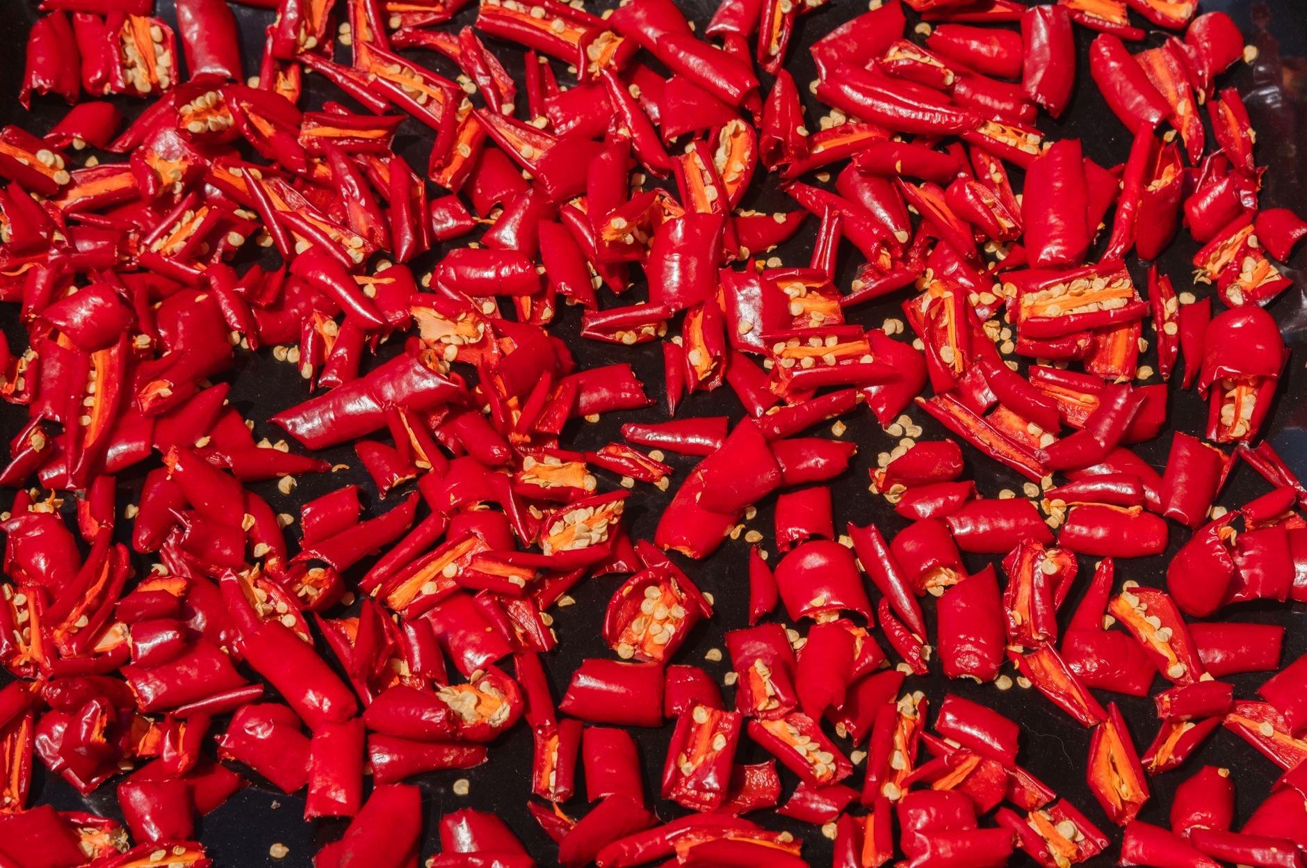 Close-up of vibrant sliced red chili peppers on a dark background, showcasing their spicy seeds.